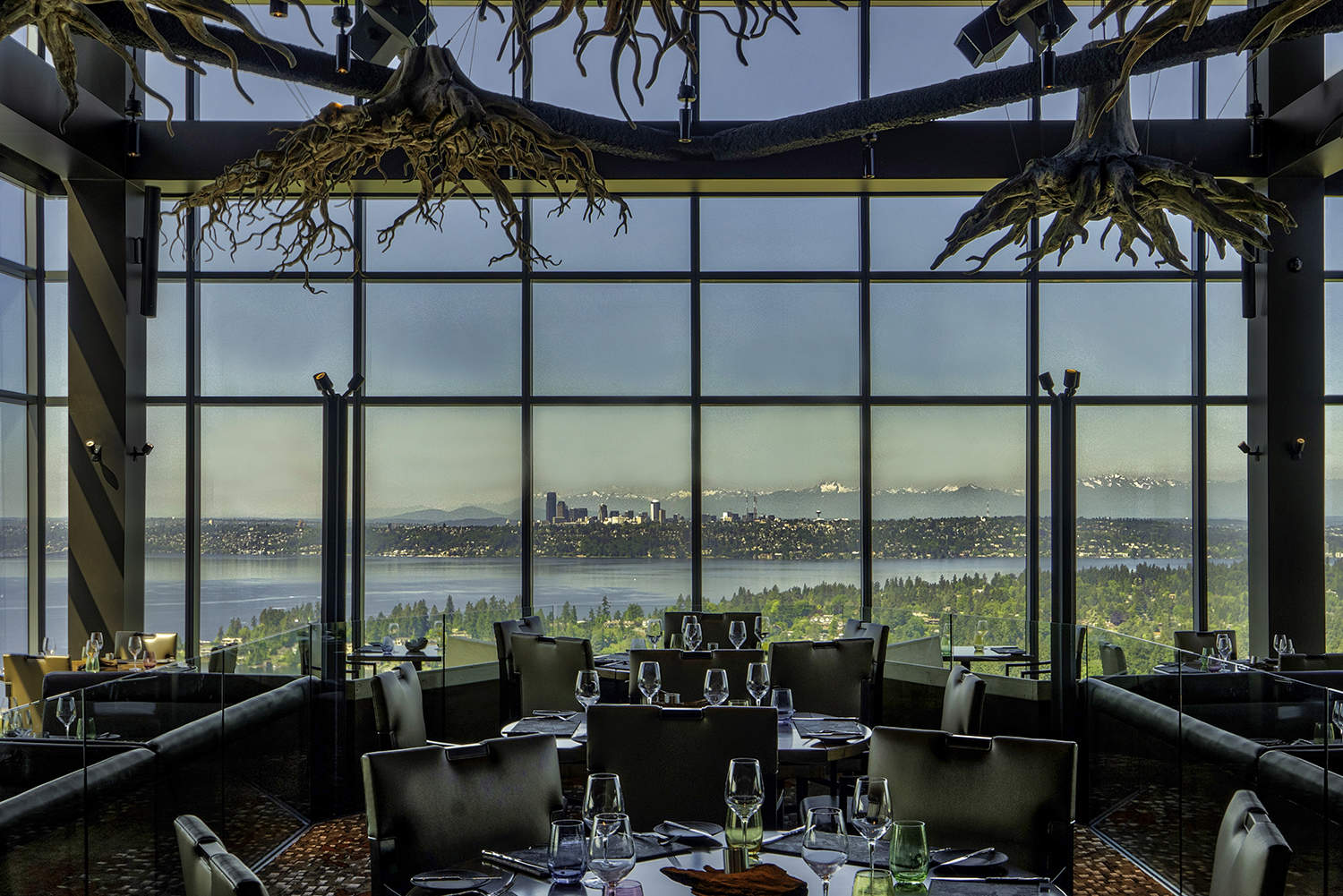 Bellevue fine dining restaurant dining room with view of Lake Washington and Seattle skyline and tree trunks above spacious tables