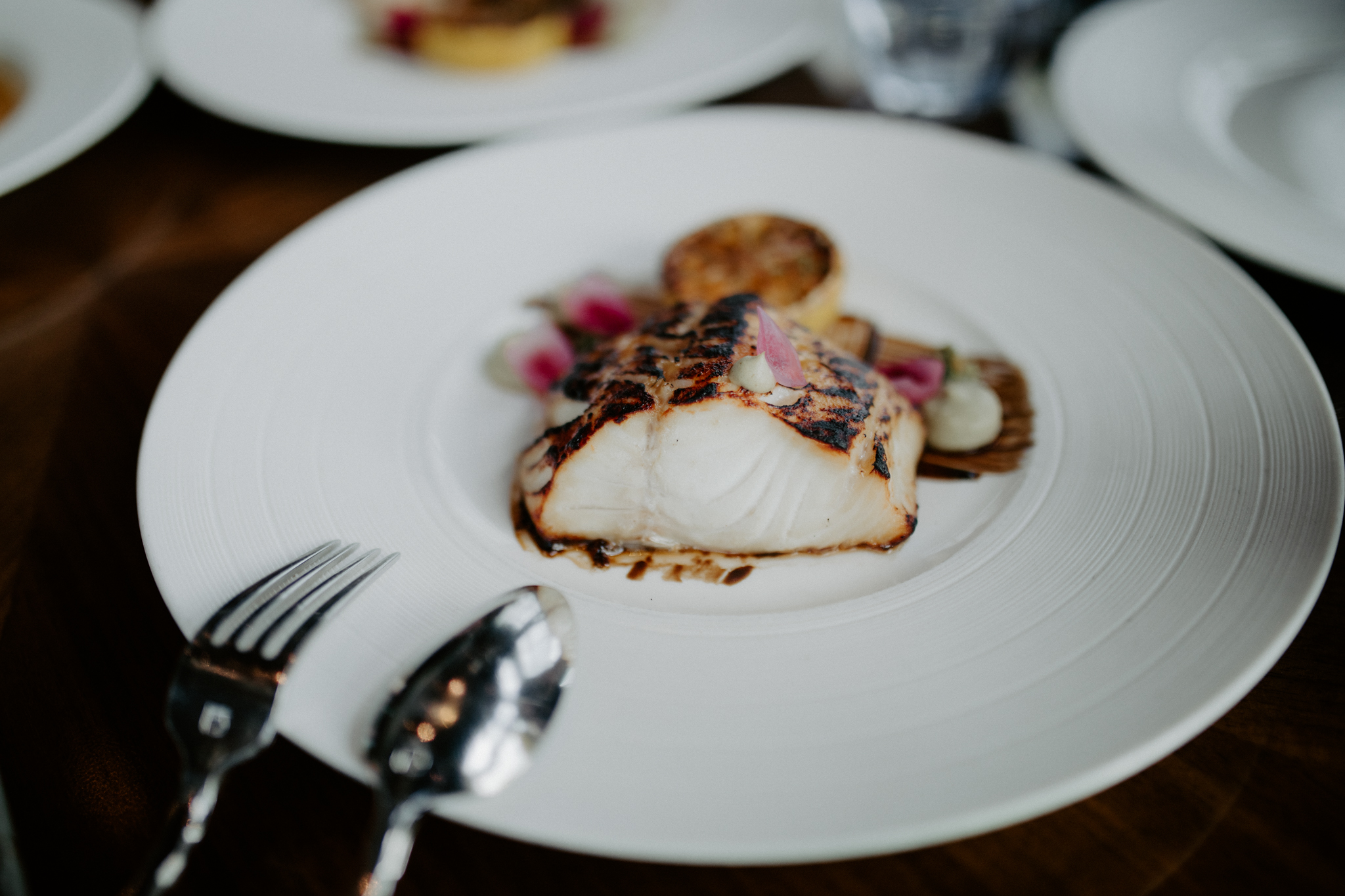 Miso Black Cod with black garlic puree, celery root puree, mint pesto, shichimi togarashi charred lemon, and pickled red onion.